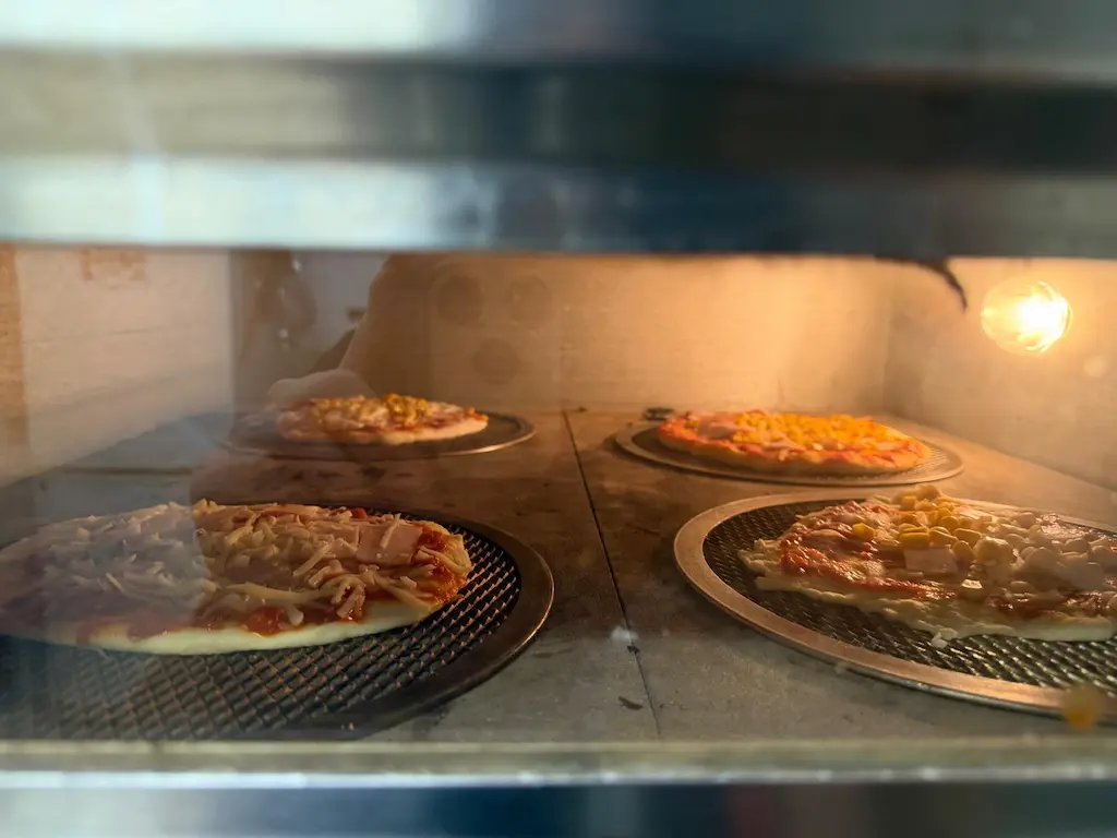 Pieczenie pizzy przygotowanej przez dzieci podczas warsztatów kulinarnych Górskiej Akademii